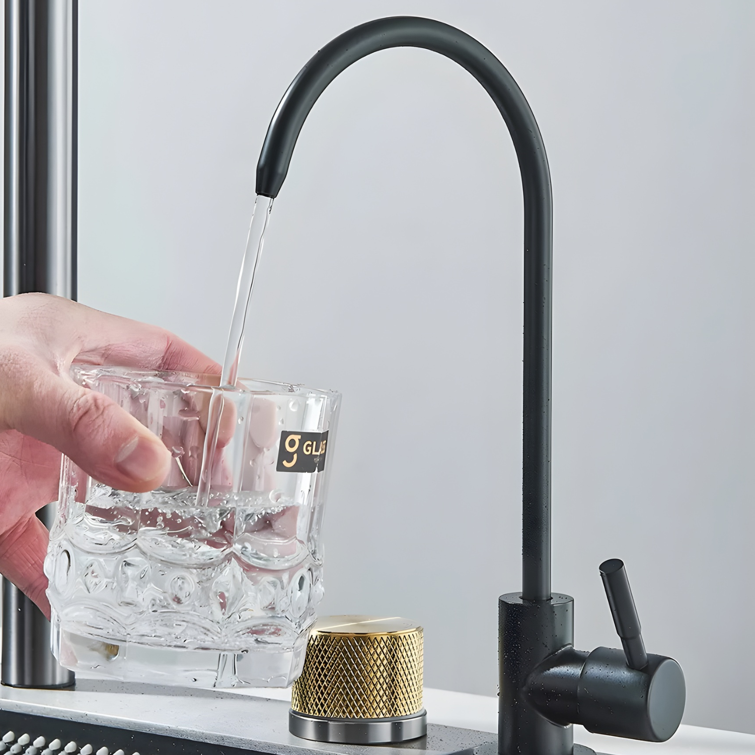 Black faucet pouring water into a glass with a blurred background