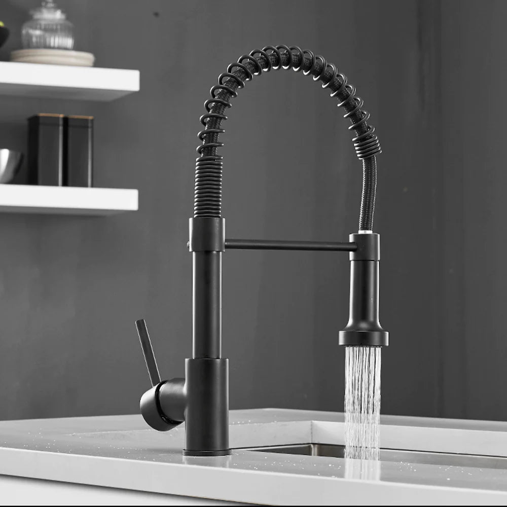 Black Halmstad pull-out kitchen faucet splashing water in a luxurious kitchen